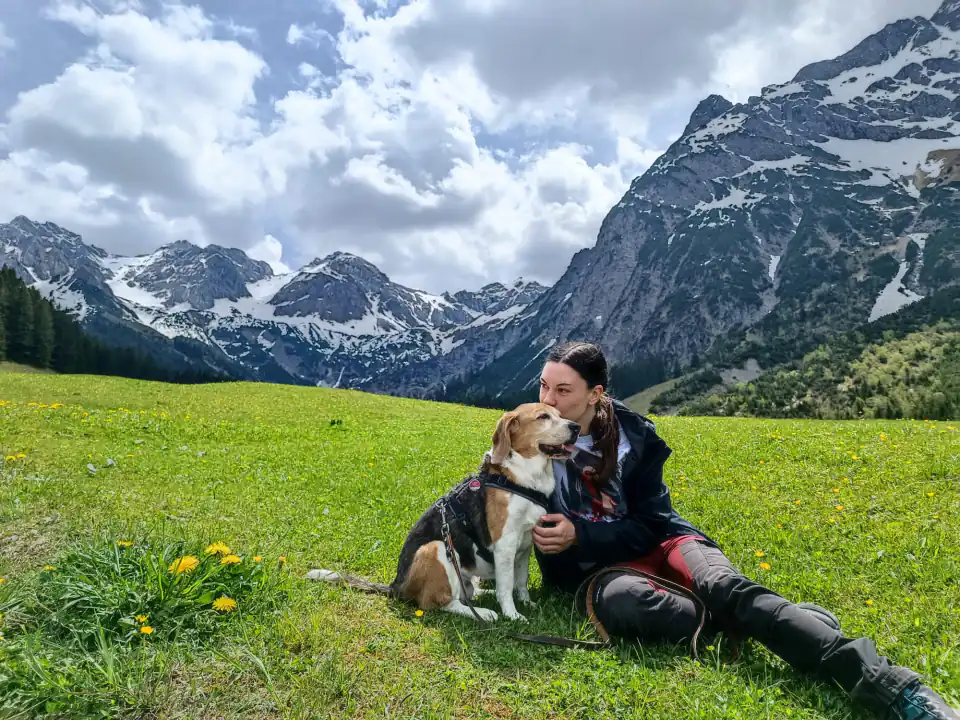 Anna Prädel sitzt mit ihrem Hund auf einer Bergwiese beim Training